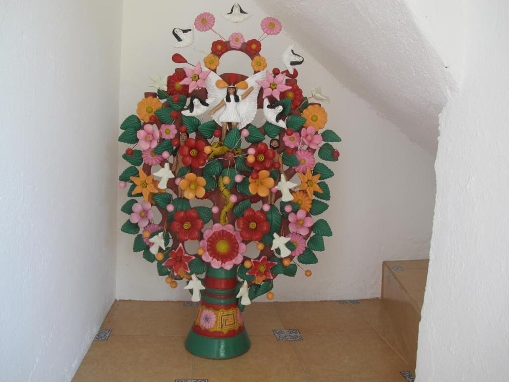 Une sculpture d’arbre décorative et colorée, ornée de figures d’anges et de fleurs.