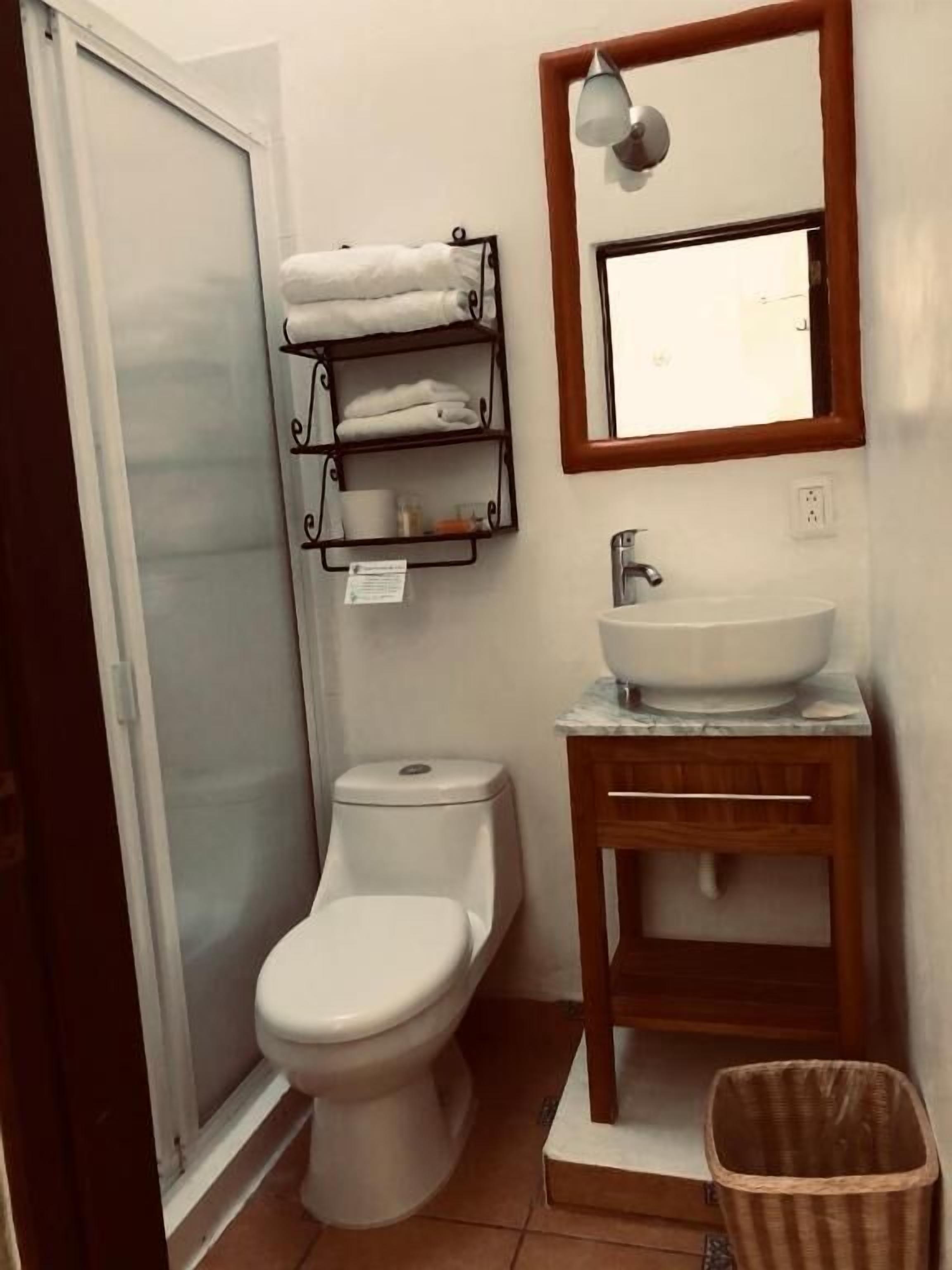 Un baño con inodoro, lavabo, espejo y toallero.