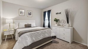 A bedroom with a bed, bedside table, dresser, and a wall-mounted sign. - Incredible Stay Fast Wifi Fully Equipped (San Antonio)