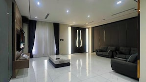 A modern living room with a sofa, a coffee table, and a TV. - Villa Chee (Sekinchan)