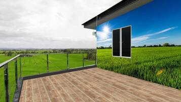 A balcony with a view of a green field and a clear sky.