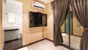 A modern hotel room with a flat-screen TV mounted on the wall, a built-in sink, and a large window with curtains. - Villa Chee (Sekinchan)
