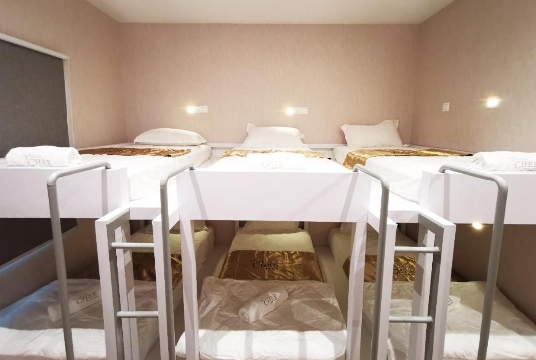 A hotel room with three single beds, each with a white mattress and a gold accent.