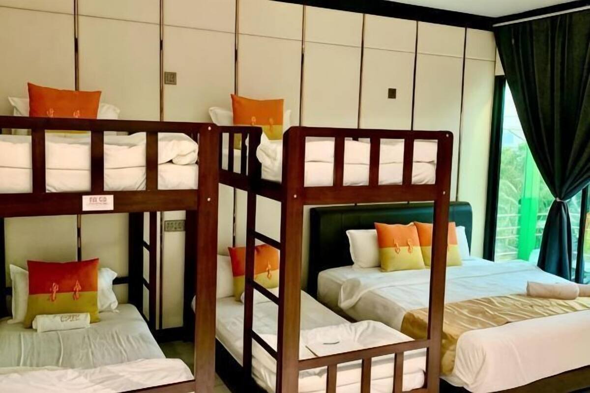 A hotel room with bunk beds, a large window with curtains, and a view of greenery outside.