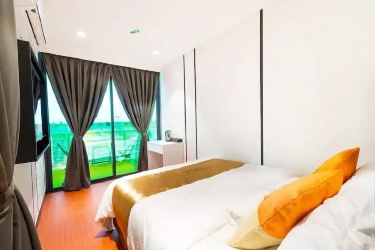 A hotel room with a bed, curtains, a view of the outdoors, and a small bathroom area.