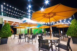 An outdoor dining area with multiple tables and chairs, surrounded by large yellow umbrellas. - Villa Chee (Sekinchan)