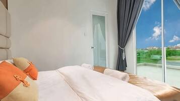 A bedroom with a large bed, a door, and a view of a landscape through a window.