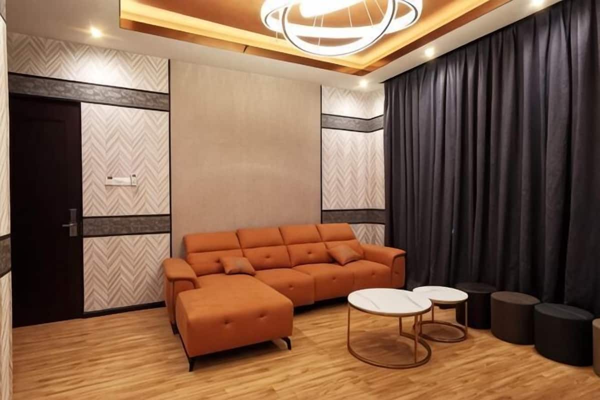 A modern room with a sectional sofa, two small round tables, a dark curtain, and a patterned wall.