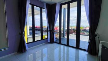 A room with large windows, a tiled floor, and curtains.