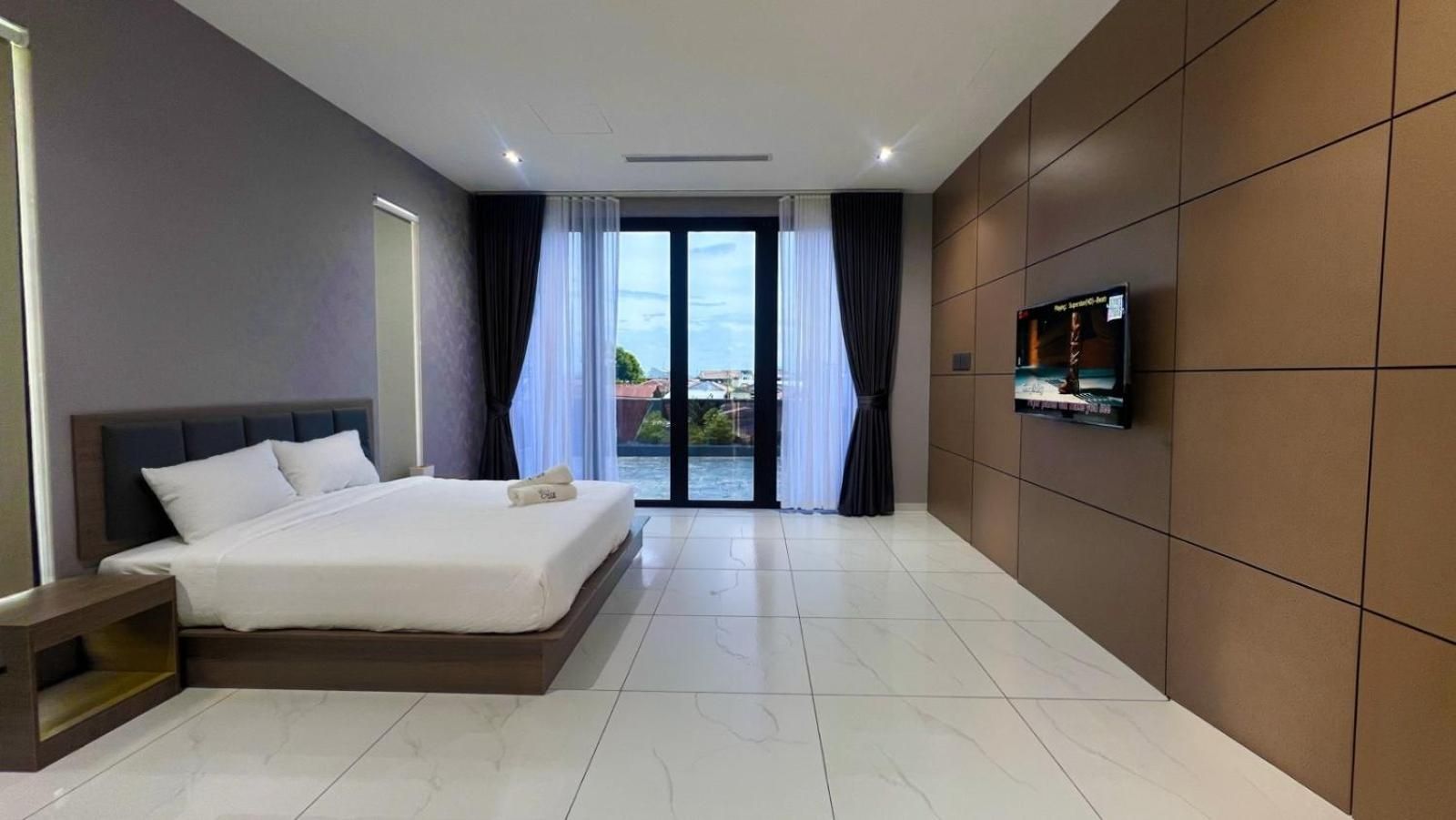 Habitación de hotel moderna con una cama grande, un televisor montado en la pared y vistas a través de la puerta de cristal.