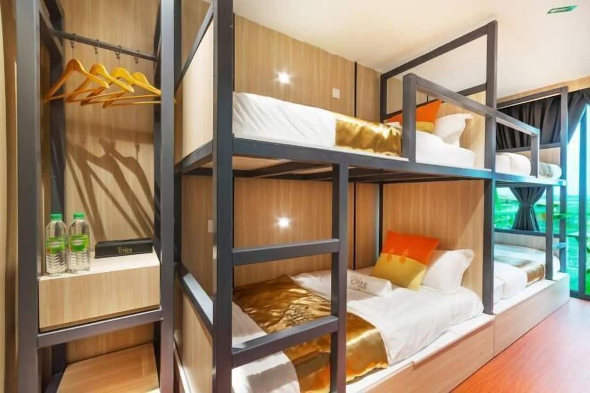 A bunk bed room with a wooden shelf, a hanging rack, and a window with a view.