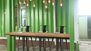 A dining area with a wooden table and chairs, green walls, and hanging light fixtures. - Villa Chee (Sekinchan)