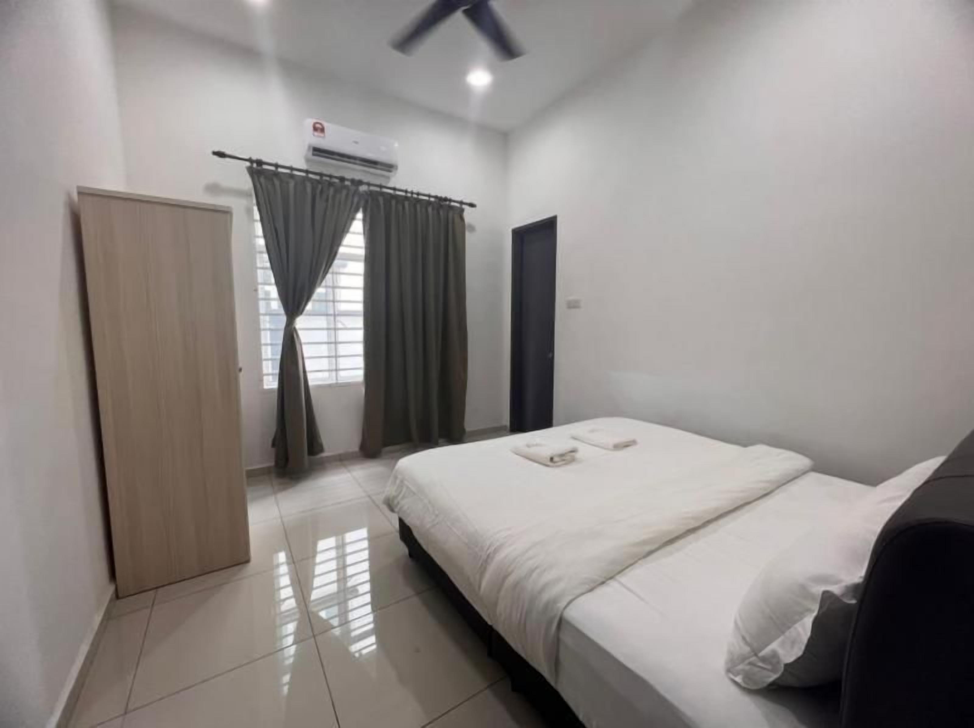 A hotel room with a bed, a wardrobe, a window with curtains, and an air conditioning unit.