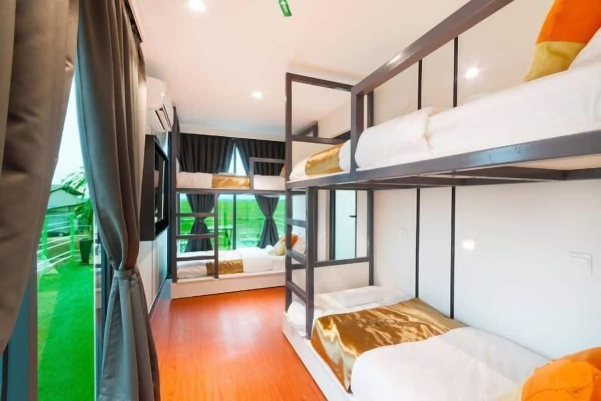 A bunk bed room with a window, a small table, and a chair.