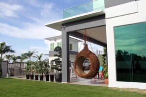 A modern house with a hanging chair, a well-maintained lawn, and a large window. - Villa Chee (Sekinchan)