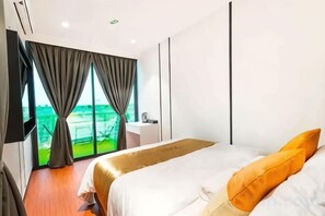A modern hotel room with a large bed, a bedside table, a TV, and a view of the outdoors. - Villa Chee (Sekinchan)