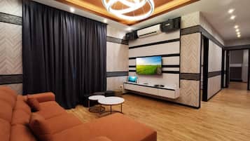 A modern living room with a sofa, a flat-screen TV, and a decorative ceiling light.