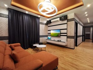 A modern living room with a sofa, a flat-screen TV, and a decorative ceiling light. - Villa Chee (Sekinchan)