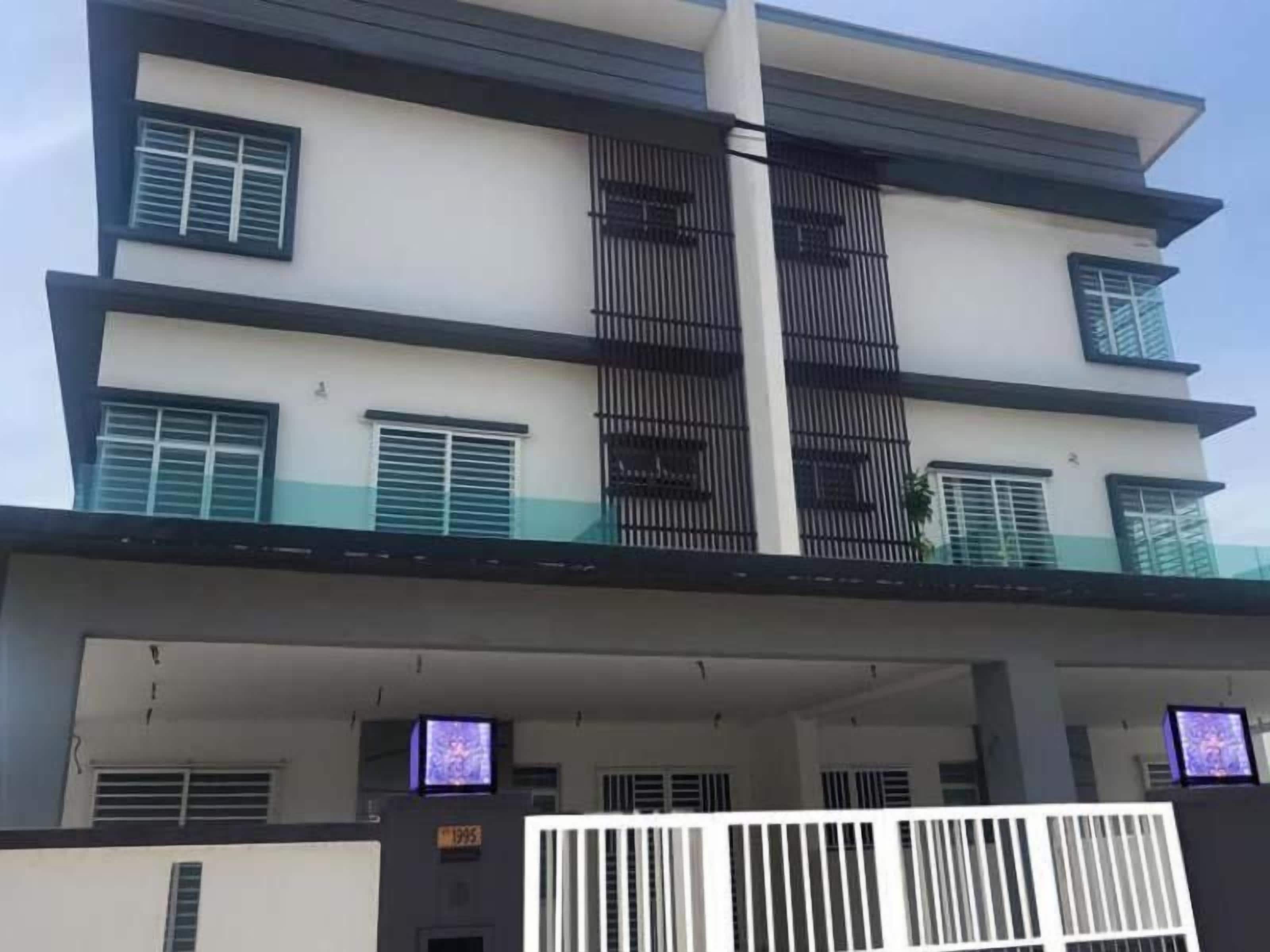 A multi-story residential building with balconies, a gated entrance, and a flat roof.