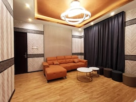 Una sala moderna con un sofá modular, mesas redondas de centro y un ventanal con cortinas.