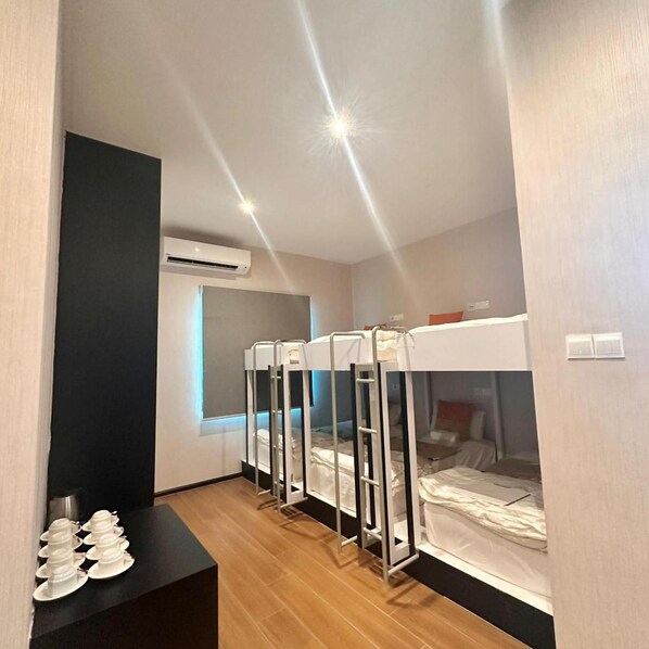 A hotel room with bunk beds, a window with blinds, an air conditioning unit, and a table with cups. - Villa Chee (Sekinchan)