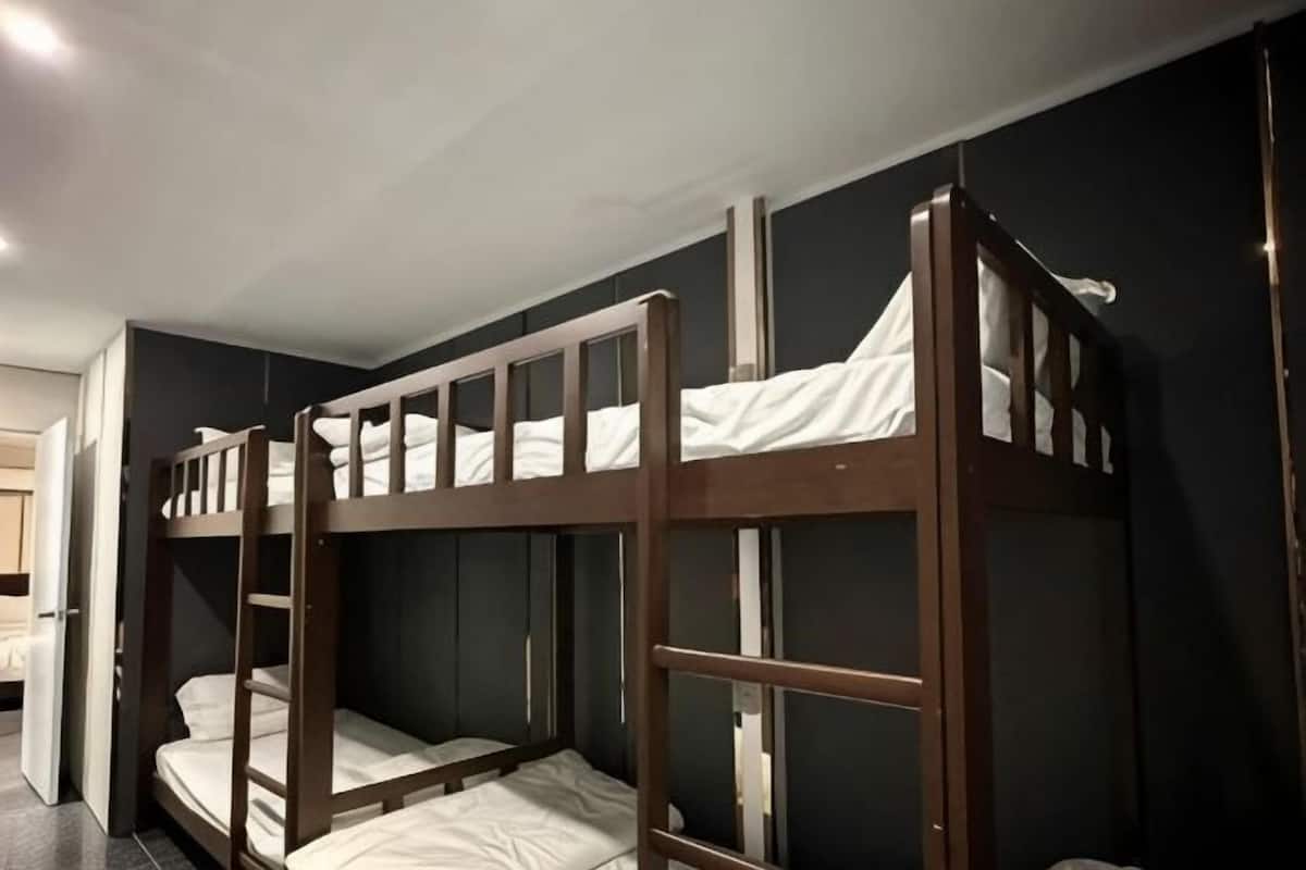 A bunk bed room with a dark wall and a door to the left.