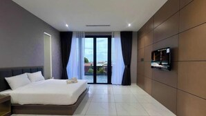 A modern hotel room with a large bed, a TV mounted on the wall, and a view through the glass door. - Villa Chee (Sekinchan)