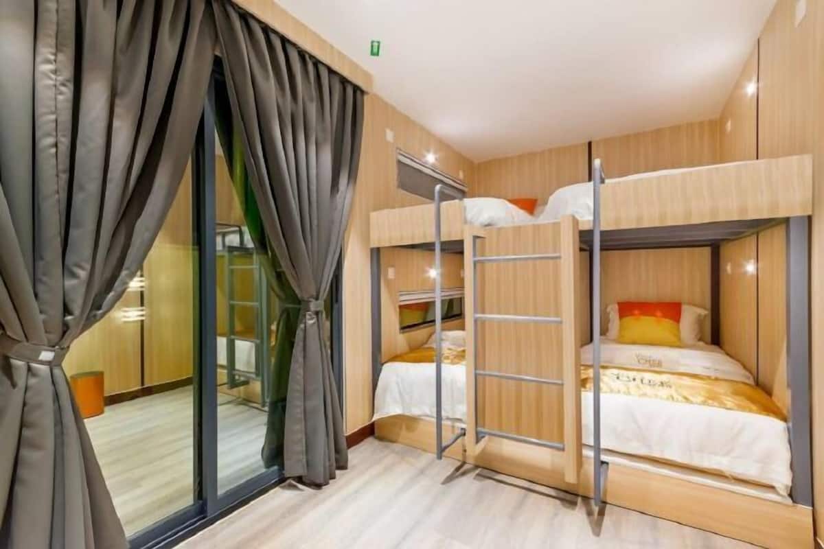 A room with bunk beds, a sliding door, and a visible trash bin.