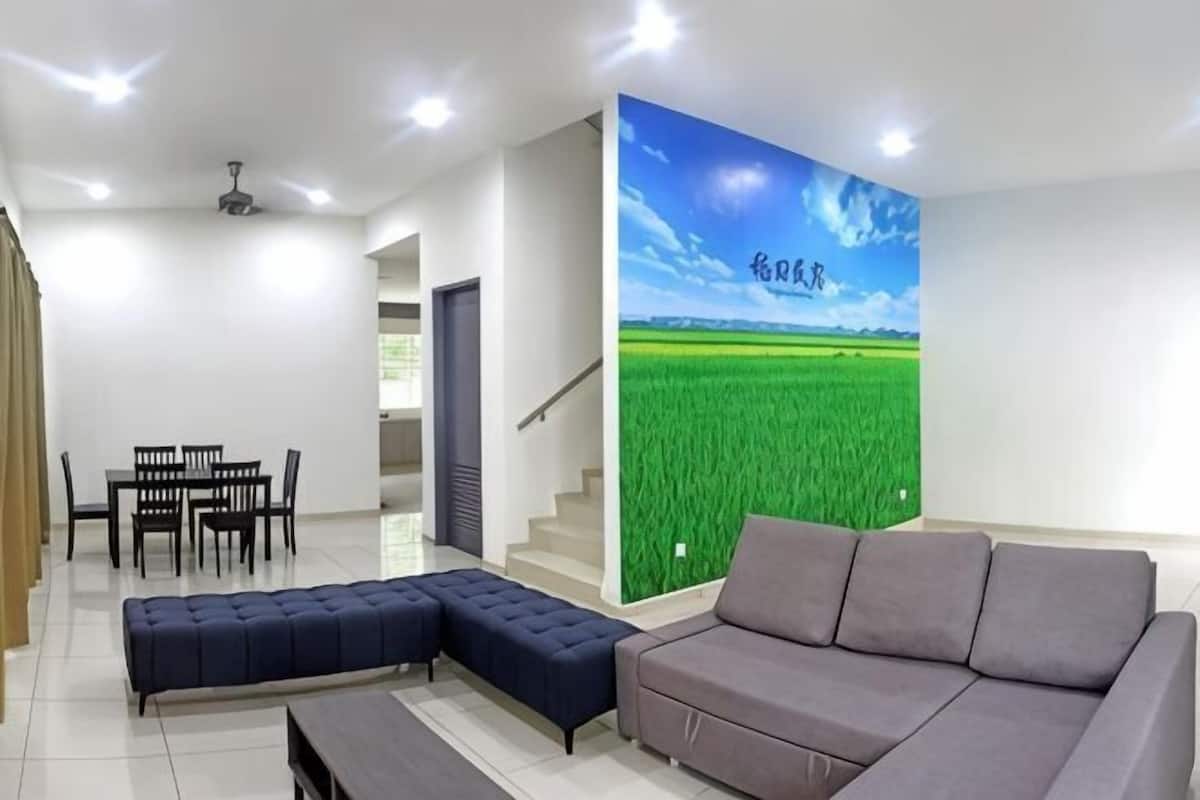 A modern living room with a sofa, ottoman, and dining area.