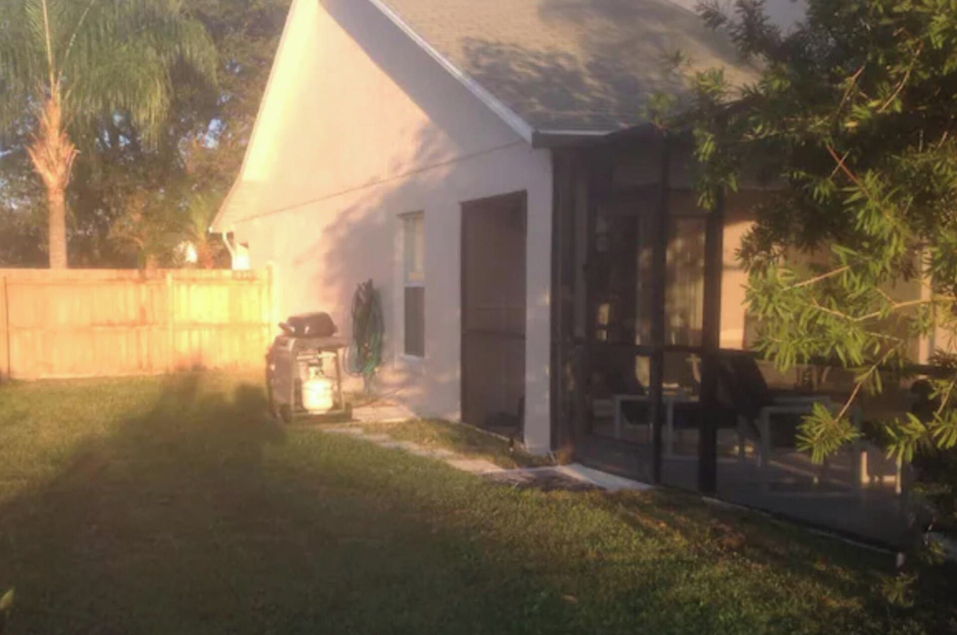 A house with a covered patio, a fenced backyard, and a lawn.