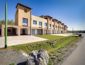 A modern building with multiple units, a paved driveway, and a grassy area. - Luxuriose Ferienwohnung am Stormthaler See (Grossposna)