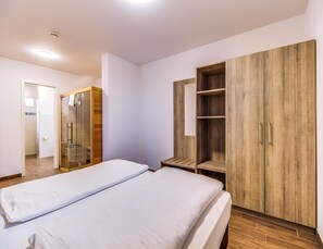 A hotel room with two beds, a wooden wardrobe, a mirror, and a shower area. - Luxuriose Ferienwohnung am Stormthaler See (Grossposna)