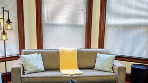 Una sala de estar con un sofá, una mesa de centro de vidrio y una lámpara de pie.