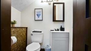 Un baño pequeño con inodoro, lavamanos y espejo.
