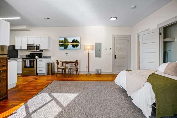 Una habitación de hotel compacta con kitchenette, zona de comedor y cama.