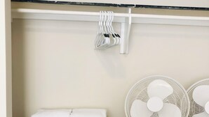 Un estante blanco con toallas y dos ventiladores de pie.