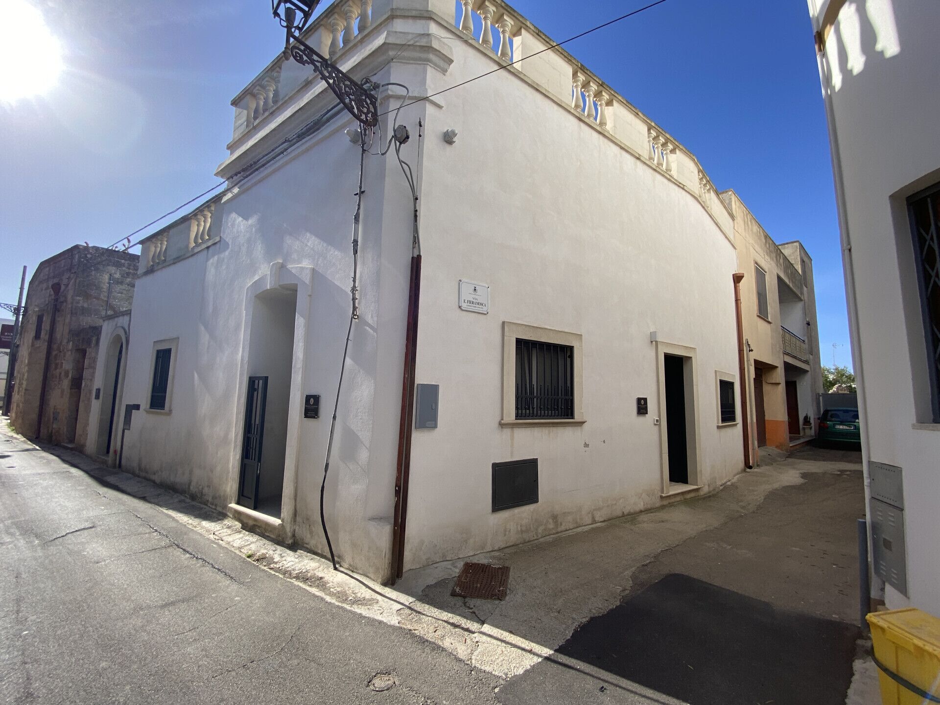 Un edificio blanco con balcón, una ventana pequeña y una puerta.
