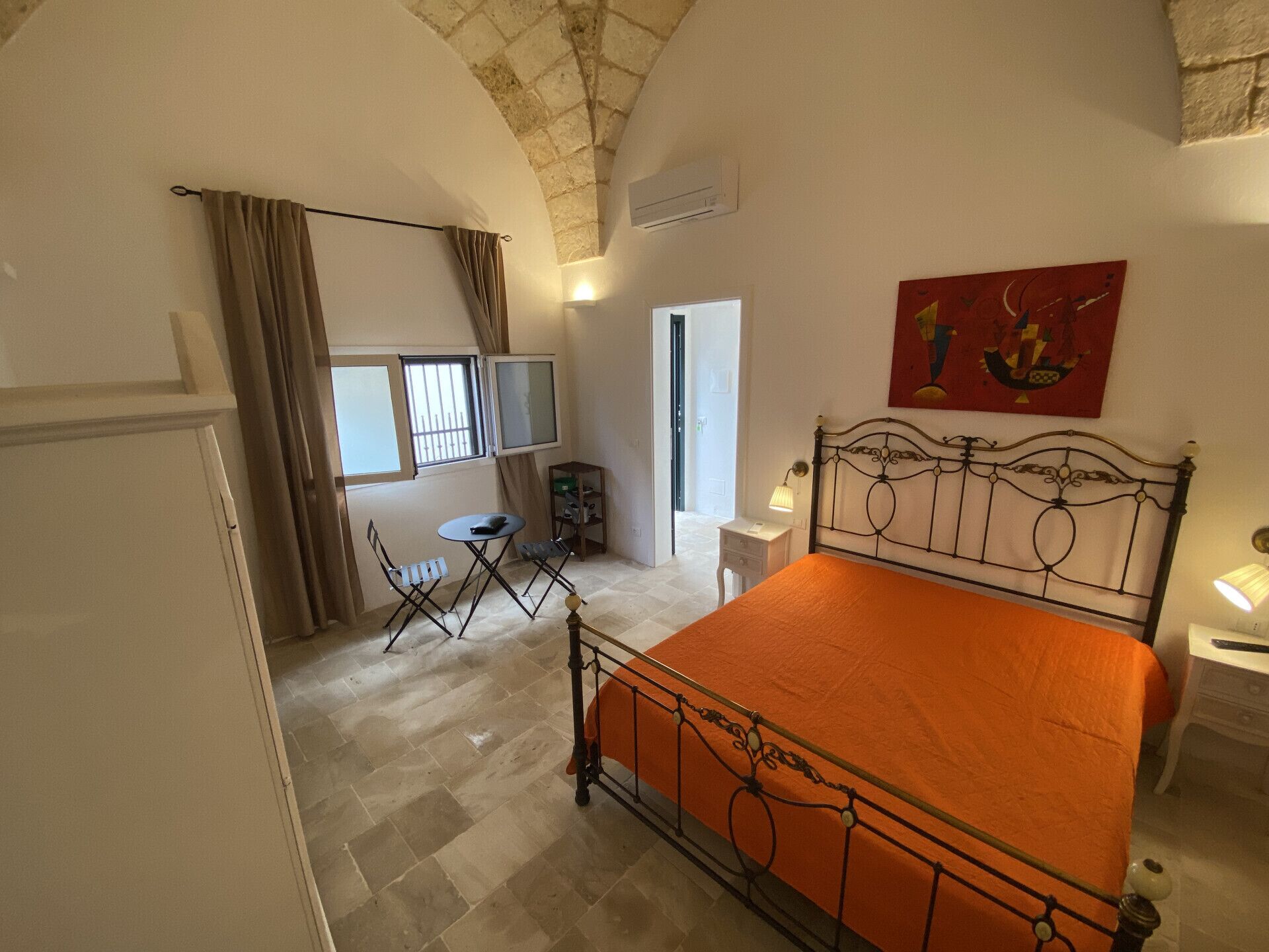 Un dormitorio con una cama, un escritorio, una silla, un televisor y un cuadro en la pared.