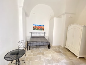Quarto com cama, uma cadeira, guarda-roupa e um quadro na parede.