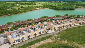 A row of modern, single-story buildings with flat roofs, arranged along a riverside. - Luxuriose Ferienwohnung am Stormthaler See (Grossposna)