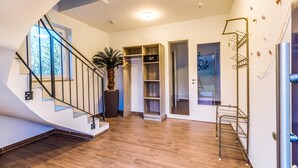 A modern interior with a wooden staircase, a potted plant, and built-in shelving. - Luxuriose Ferienwohnung am Stormthaler See (Grossposna)