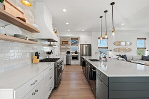 Una cocina moderna con armarios blancos, electrodomésticos de acero inoxidable e iluminación colgante.