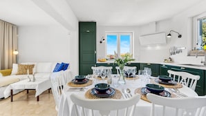 A dining area with a round table set for four, white chairs, and a view of the city through a window. - Awesome home in Vodice (Vodice)