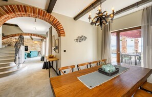 Relax in this stylish space with a large dining table, comfortable sofa, and a unique arched brick feature.