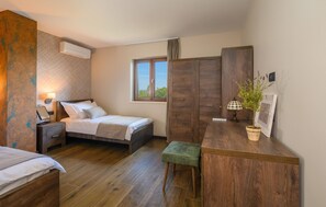 Cozy retreat with a comfortable bed, nightstand, and bedside table, plus a desk with a lamp and a wardrobe.