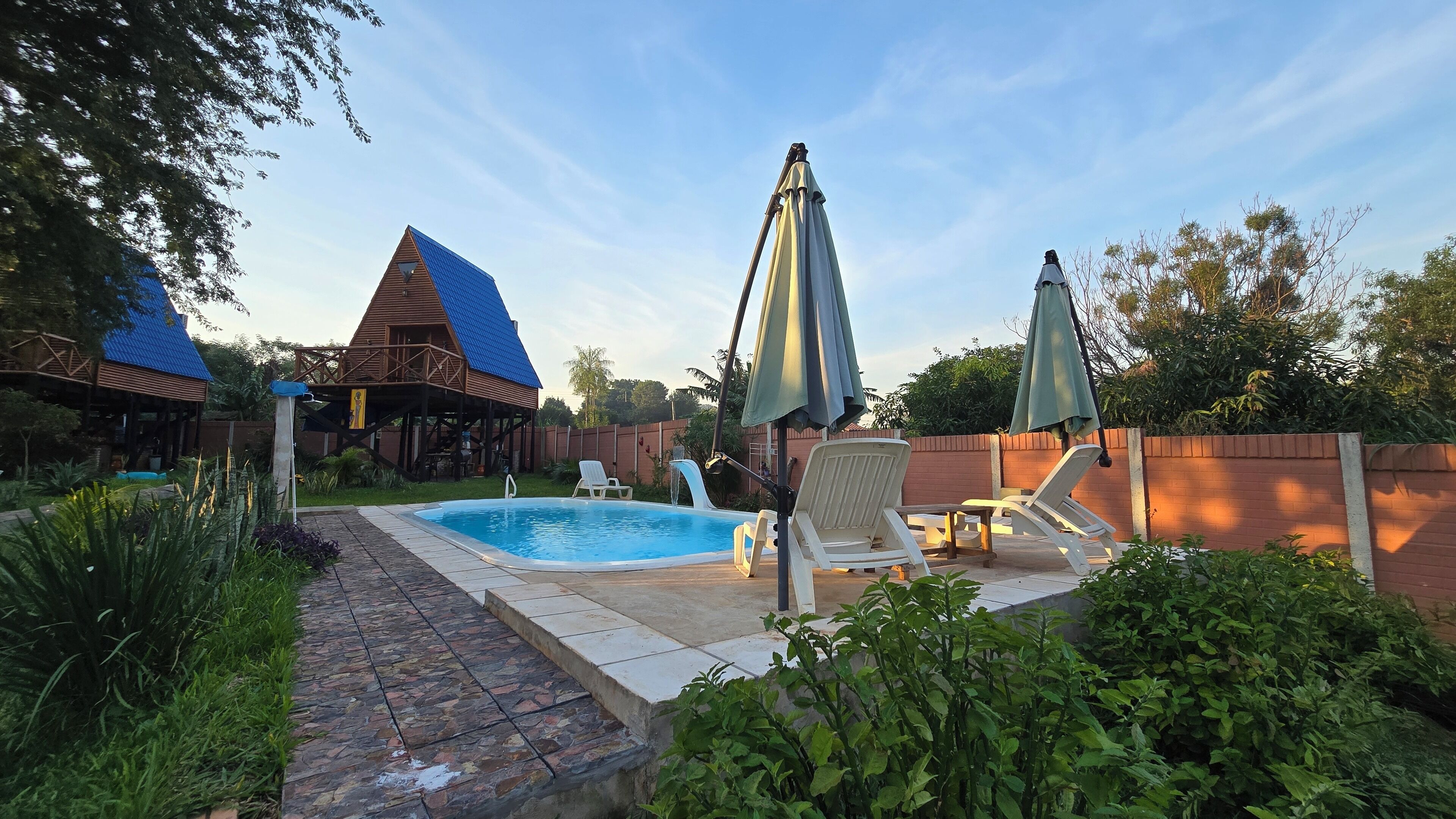 Un patio trasero con piscina, sillas de descanso y una terraza de madera.