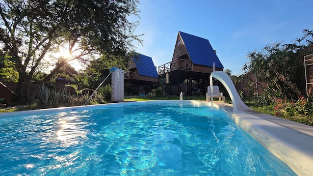Una piscina con agua cristalina, rodeada de abundante vegetación y una terraza de madera.