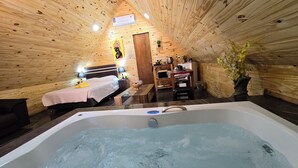 Una cabaña de madera acogedora con un dormitorio, un baño con bañera de hidromasaje y una kitchenette.