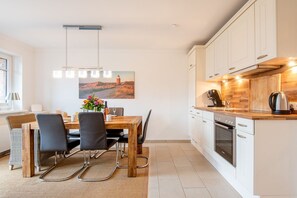 Une cuisine moderne avec des armoires blanches, un plan de travail en bois et un four encastré.