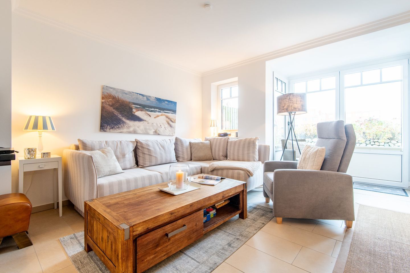 Un salon moderne avec un canapé, un fauteuil, une table basse et un tableau accroché au mur.